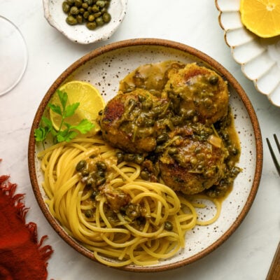 Chicken piccata meatballs with pasta and a glass of red wine.