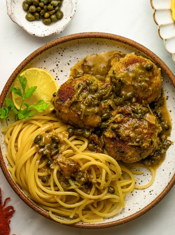 Chicken piccata meatballs with pasta and a glass of red wine.