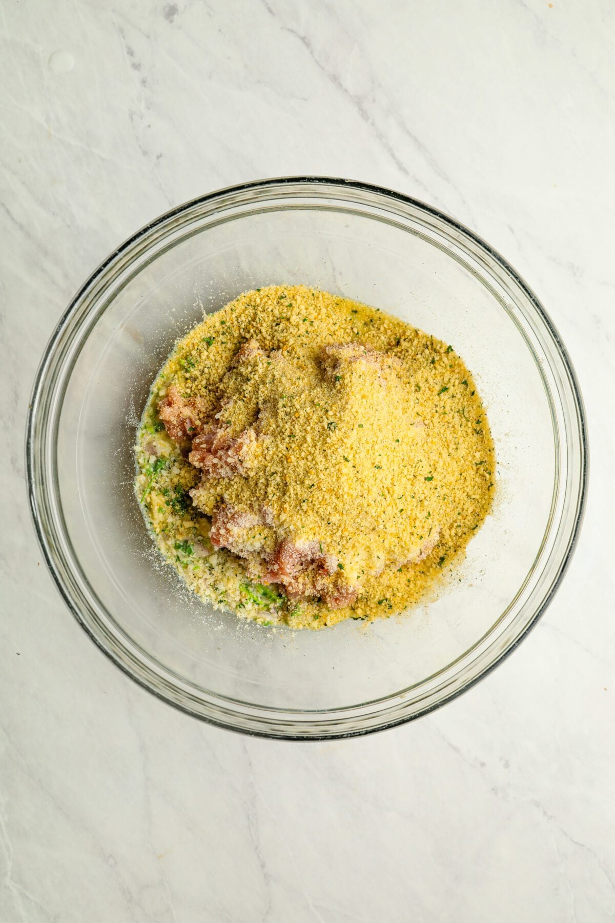 large bowl with cheese and breadcrumbs added to meatball mixture
