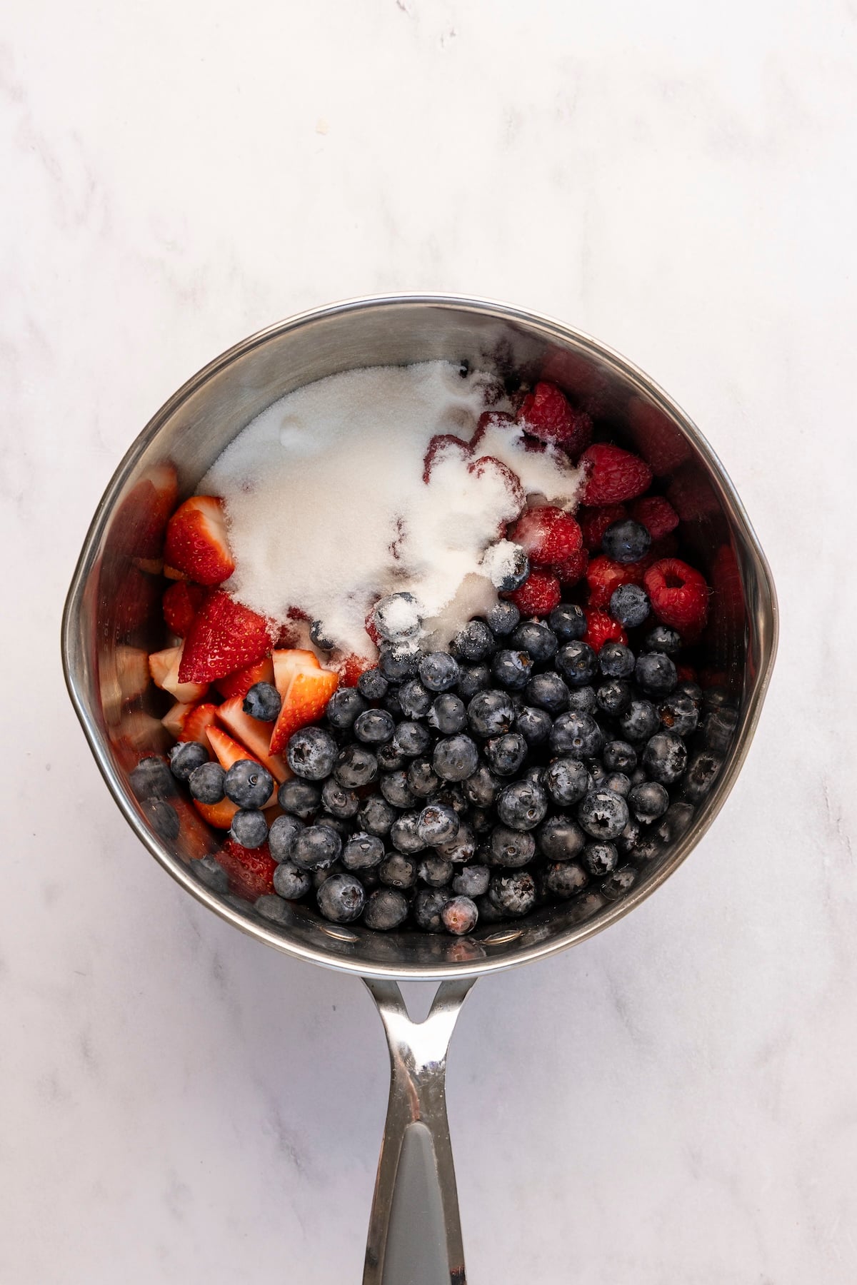 medium saucepan with strawberries, blueberries, raspberries, sugar, salt, and ¼ cup water