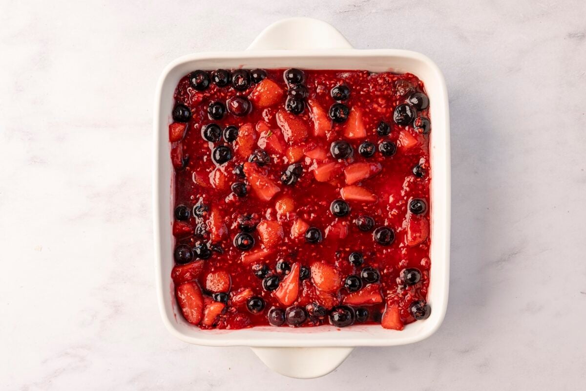 8-inch square pan with berry mixture layered over top of bread. 
