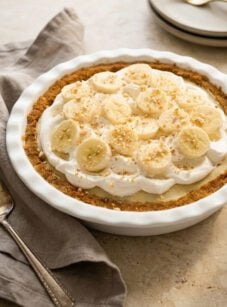 banana cream pie with a linen napkin and stack of plates