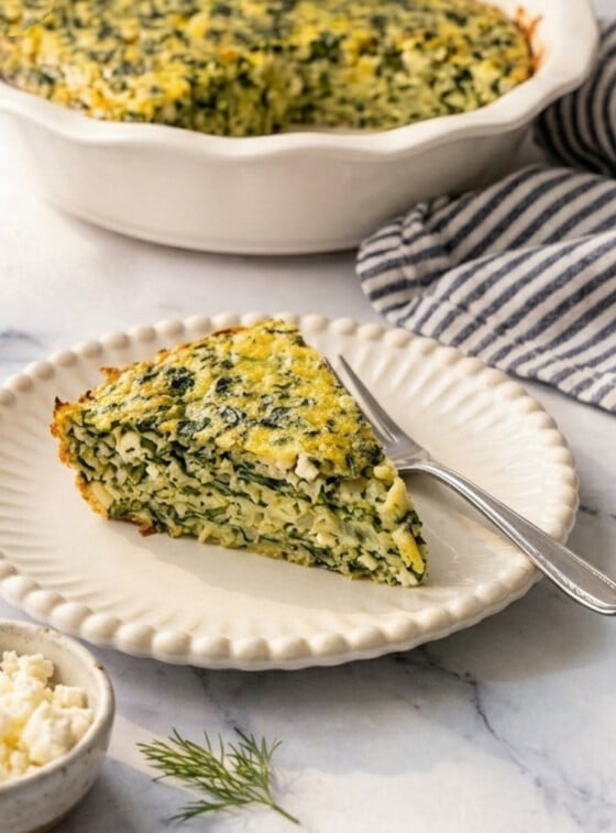 Greek spinach rice and feta pie slice on white beaded plate