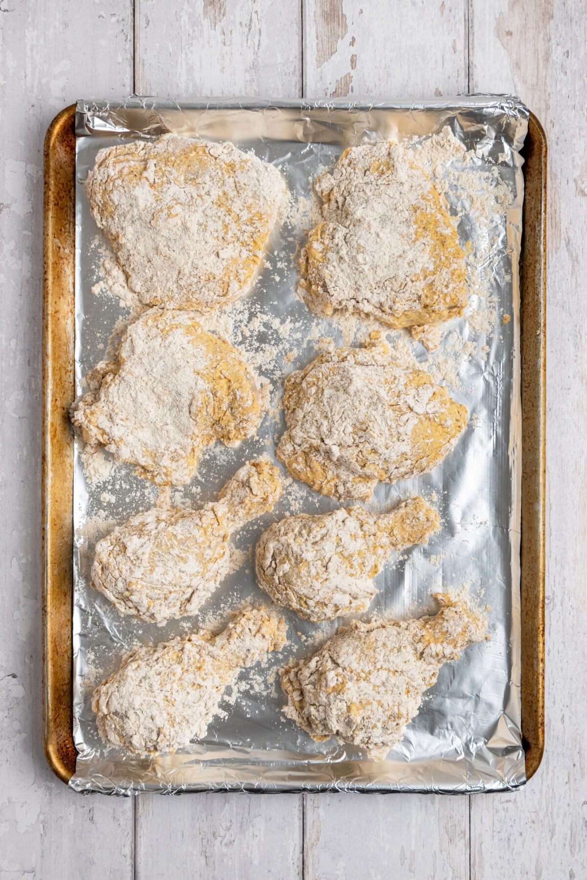 breaded raw chicken on foil lined baking sheet