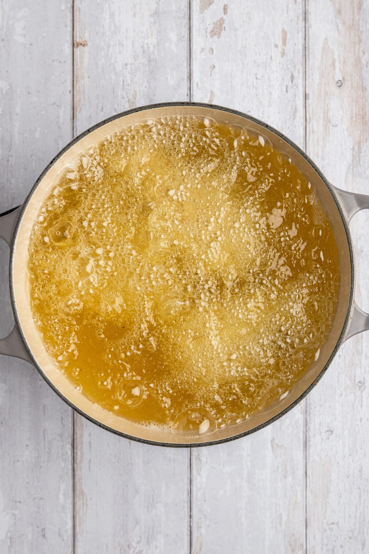 large dutch oven with uncooked chicken pieces in bubbling oil