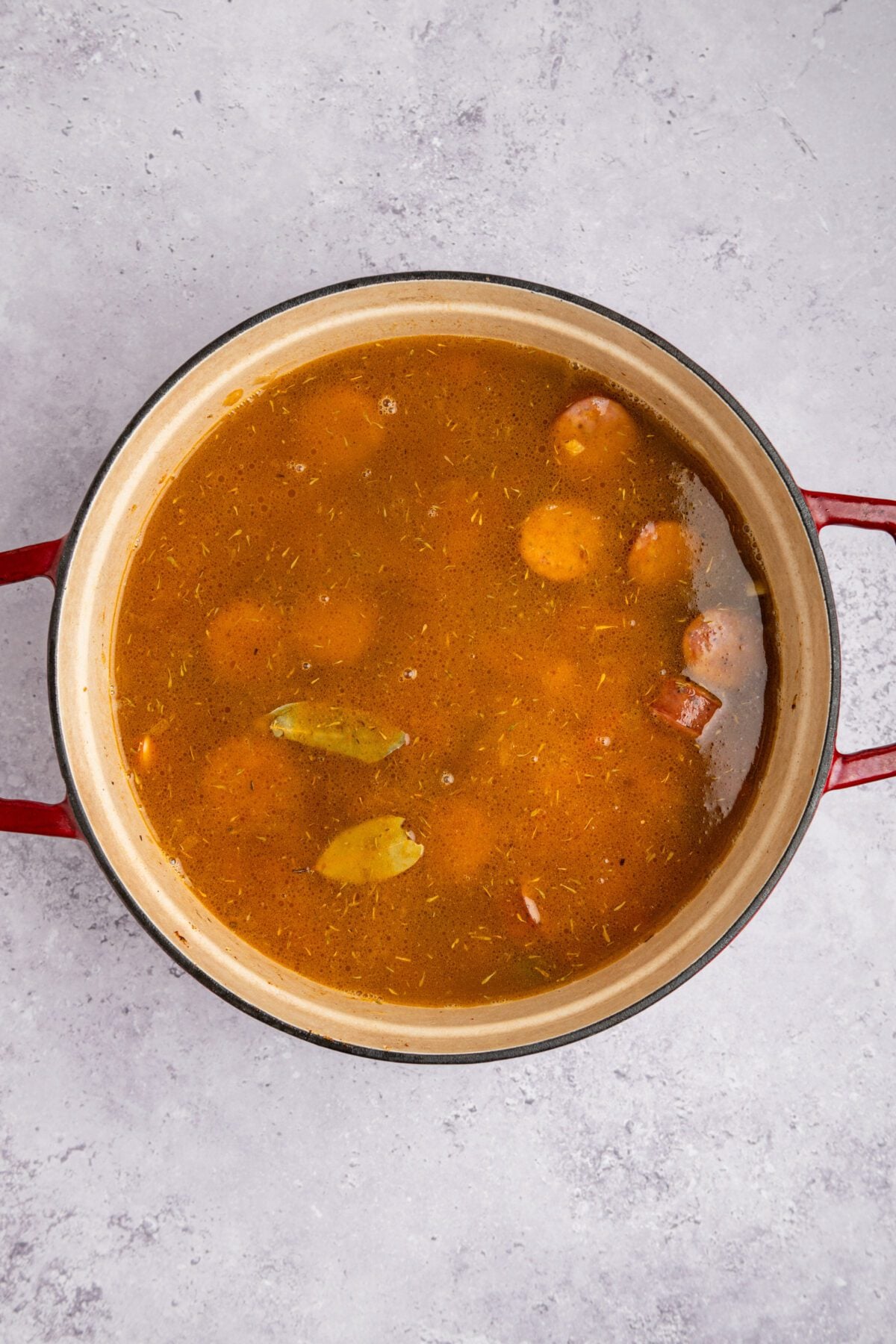 soaked beans, chicken broth, water, and bay leaves added to other ingredients in dutch oven