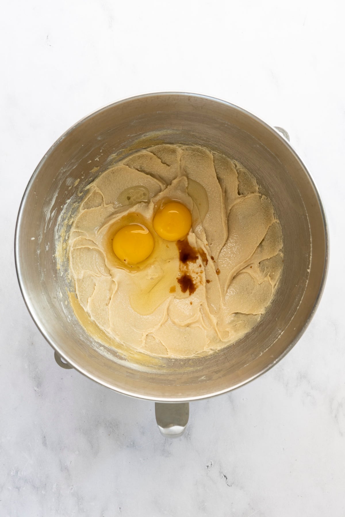 mixing bowl with egg, egg yolk, and vanilla added to butter/sugar mixture