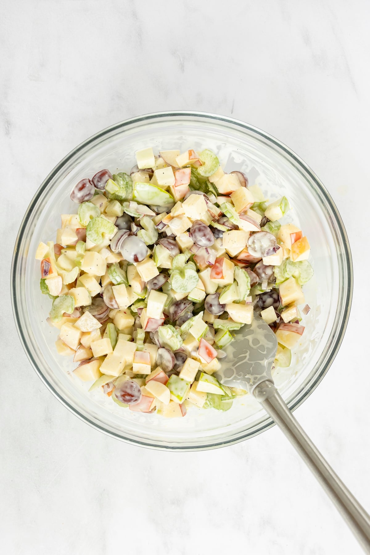 Large bowl with apples, celery, grapes, and red onion combined with dressing