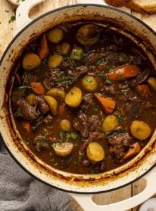 Beef stew in Dutch oven on wood table.