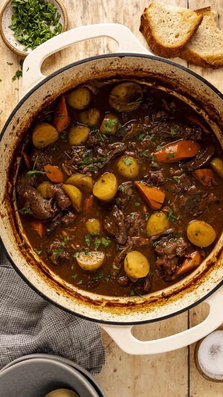 Beef stew in Dutch oven on wood table.