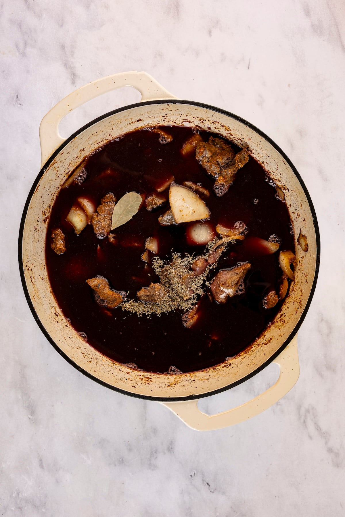 Broth, wine, water and herbs added to Dutch oven.