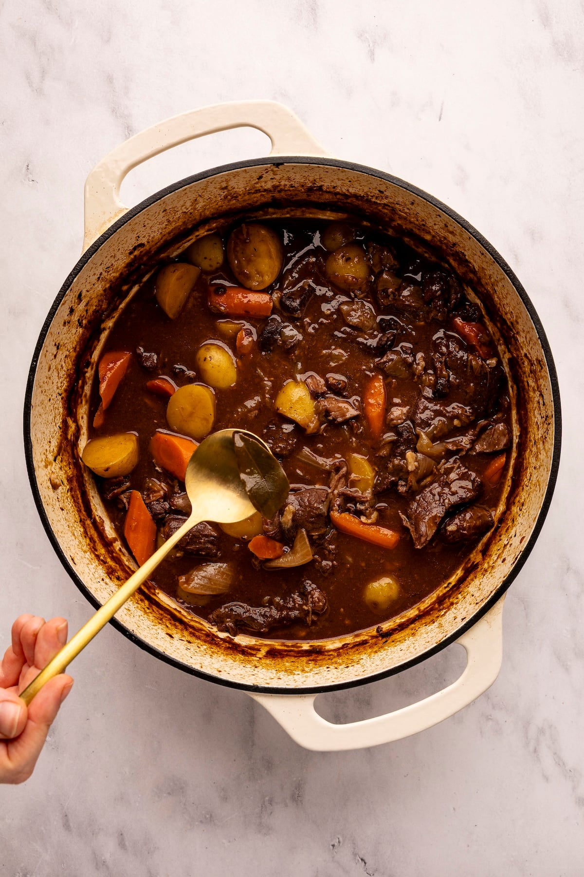 Fishing the bay leaf out of pot of beef stew.