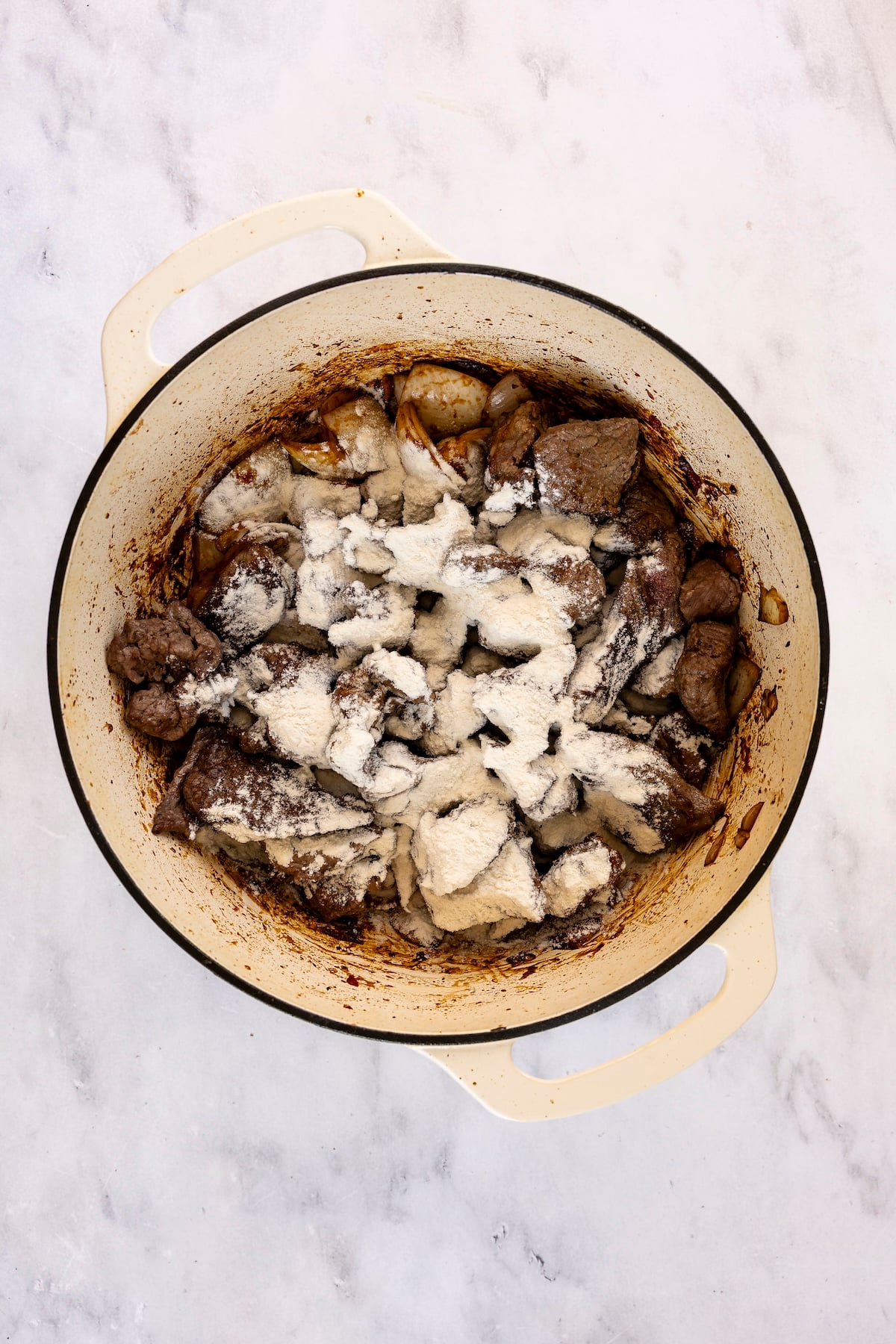 Flour sprinkled over seared beef and onions.
