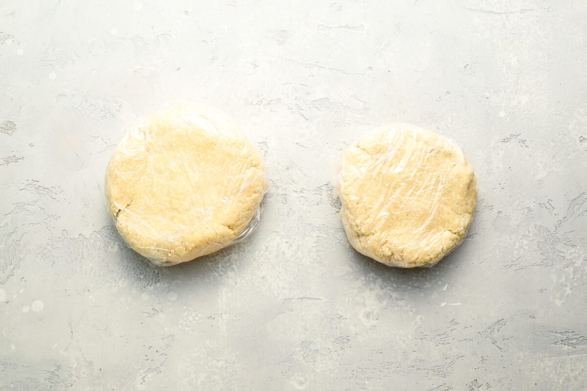 Discs of pie dough wrapped in plastic wrap.