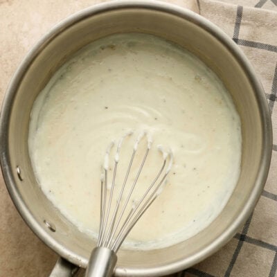 Bechamel sauce in pot with whisk.