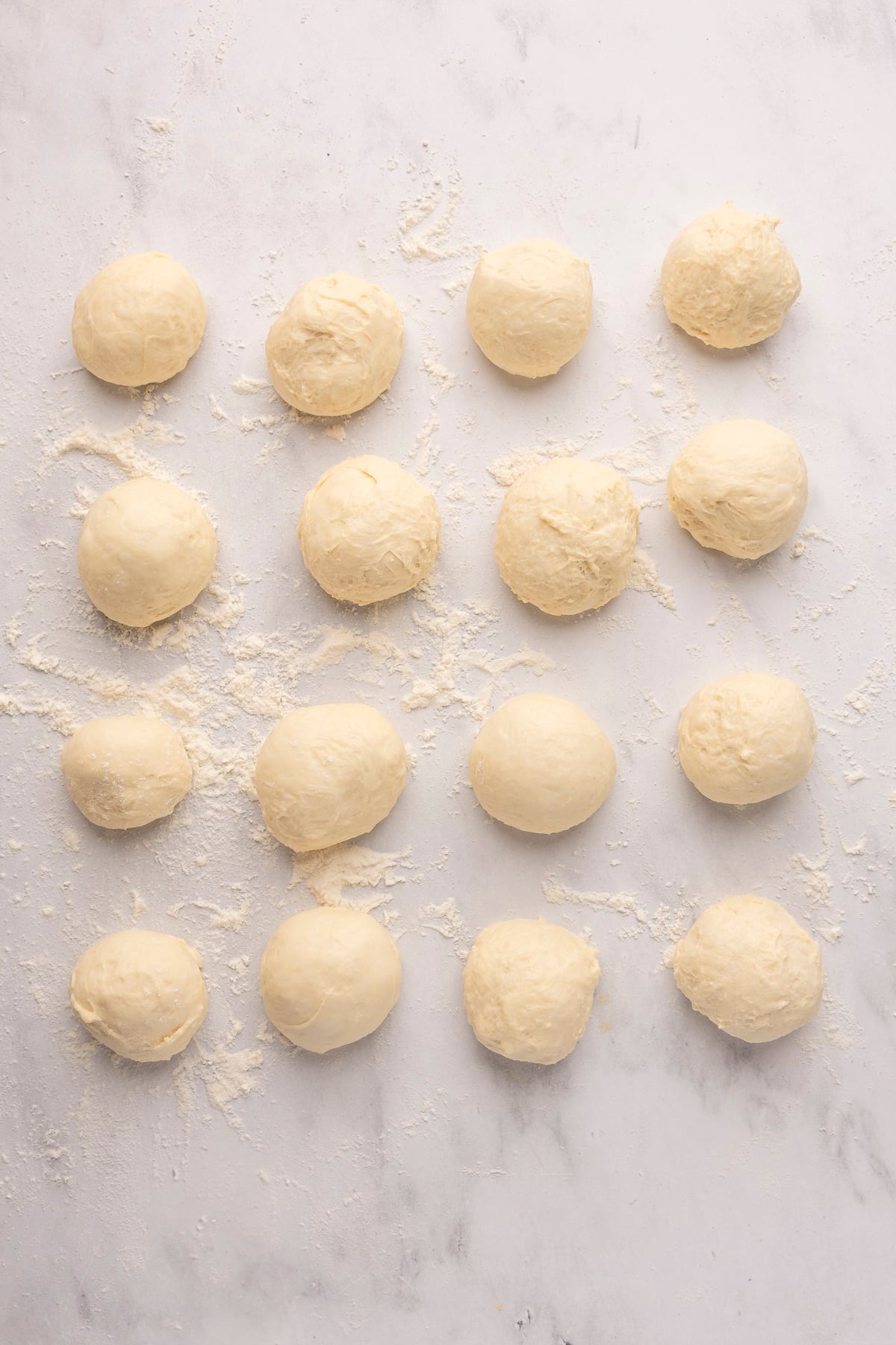 english muffin dough rolled into 16 balls on flour dusted surface
