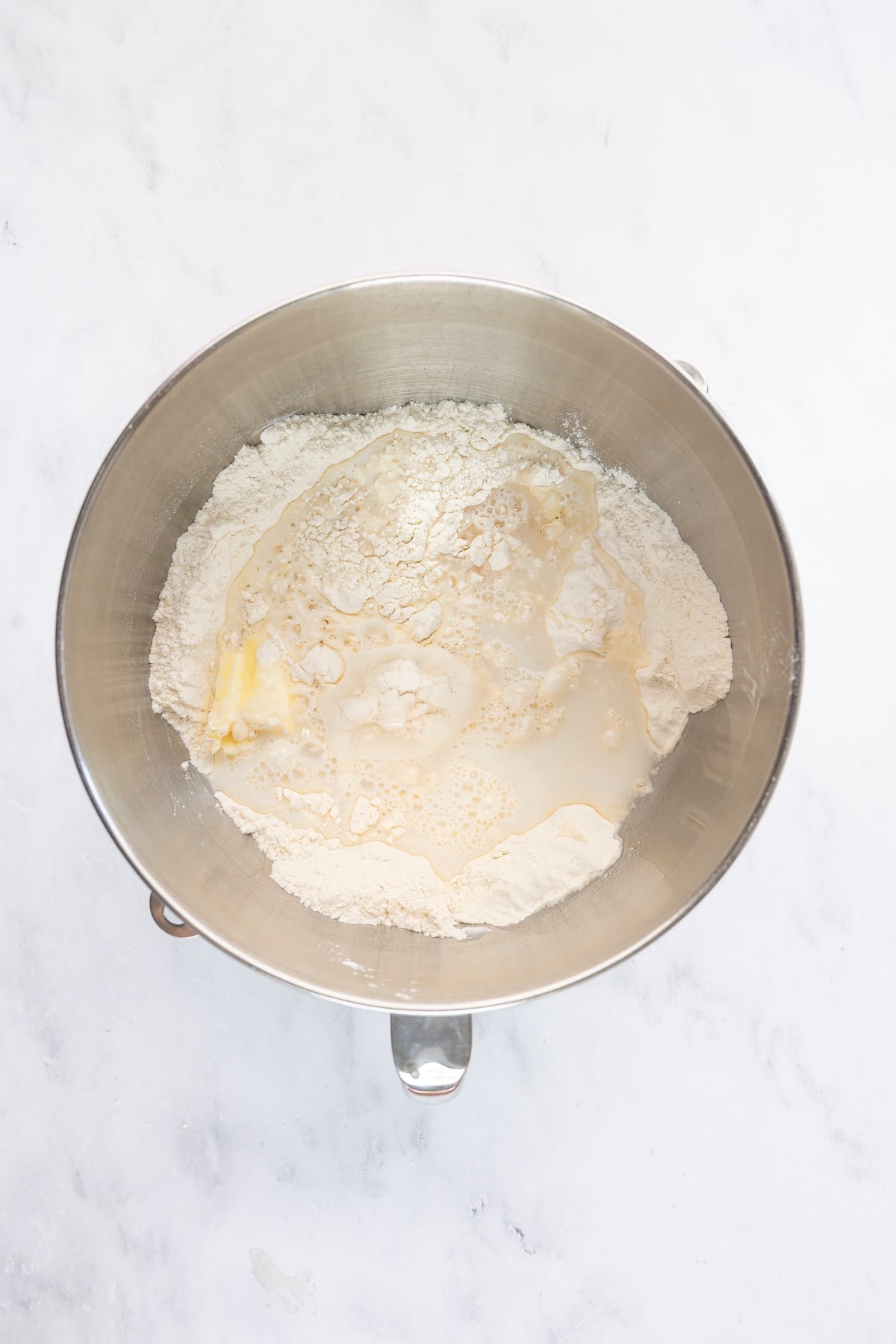 mixing bowl with butter, water, milk, and egg added to flour mixture