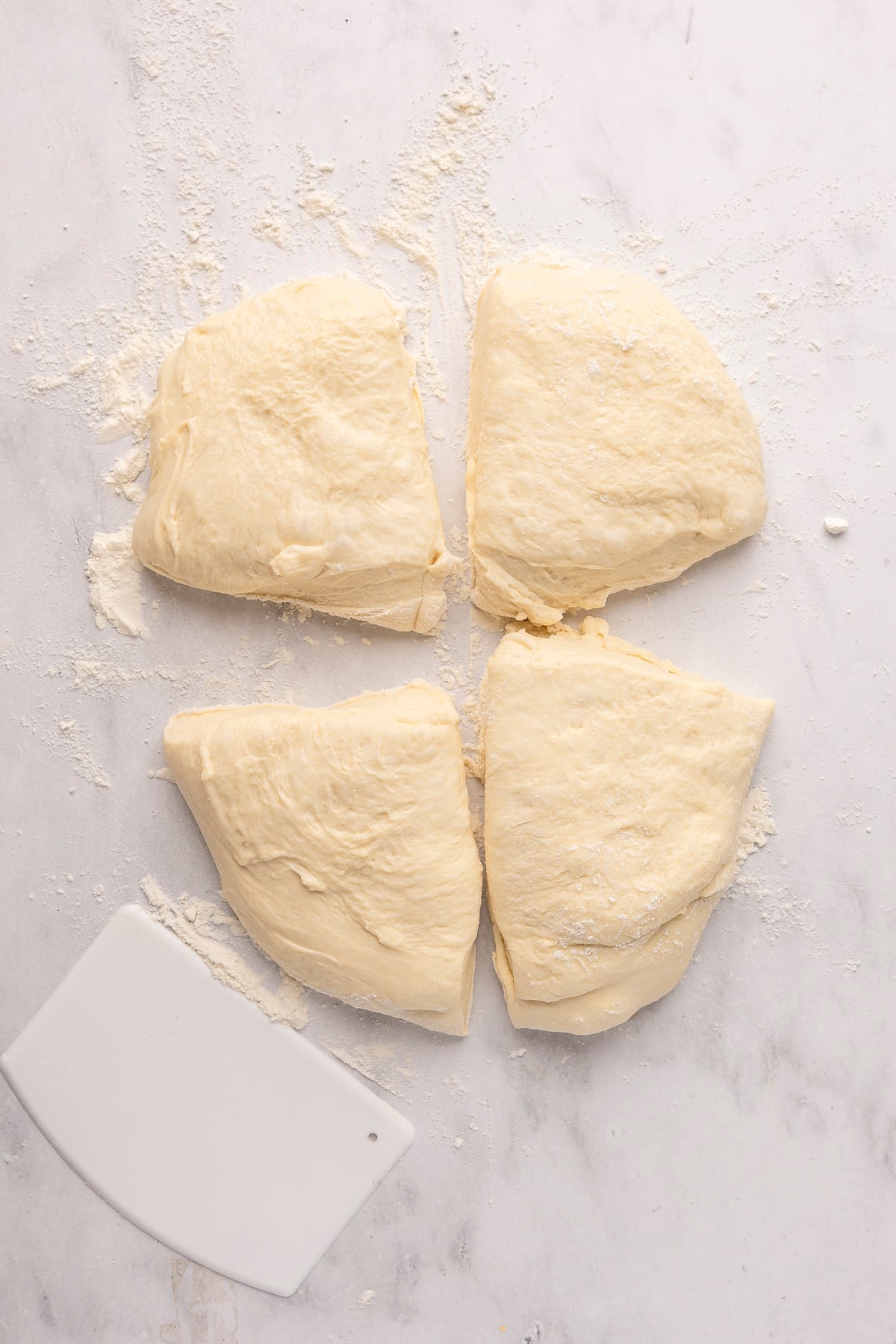 english muffin dough in in four portions on flour dusted surface