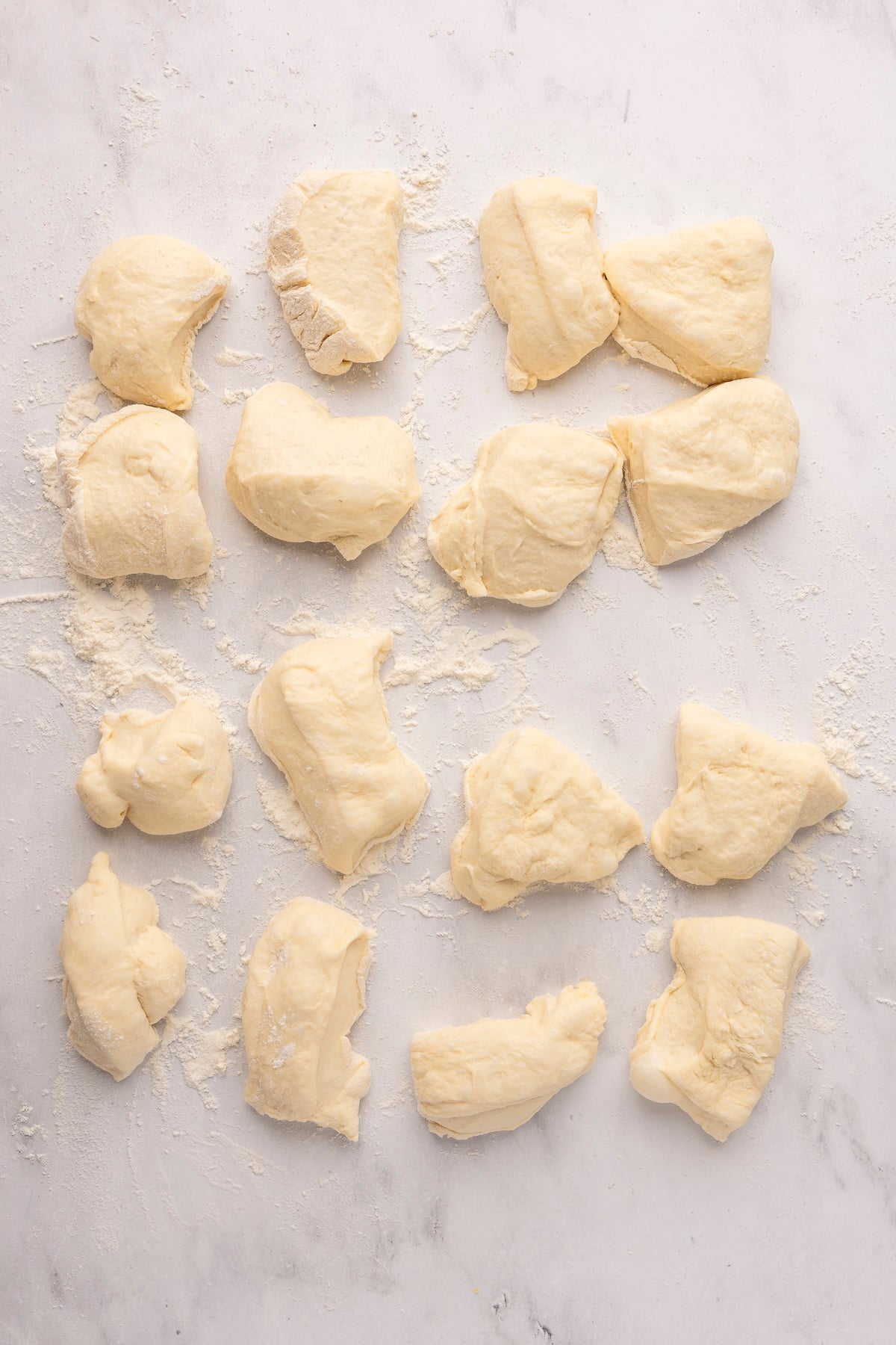 english muffin dough in 16 equal pieces on flour dusted surface
