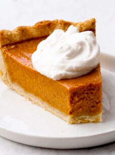 Slice of pumpkin pie topped with whipped cream.