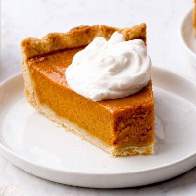 Slice of pumpkin pie topped with whipped cream.