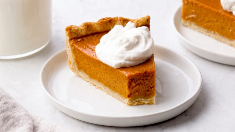 Slice of pumpkin pie topped with whipped cream.